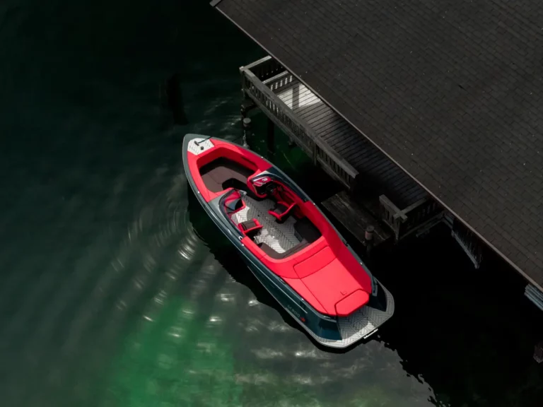 Ein elegant geparktes ABT Marian M 800-R Motorboot auf einem ruhigen See, das seine makellose schwarze Lackierung und rote Polsterung präsentiert.