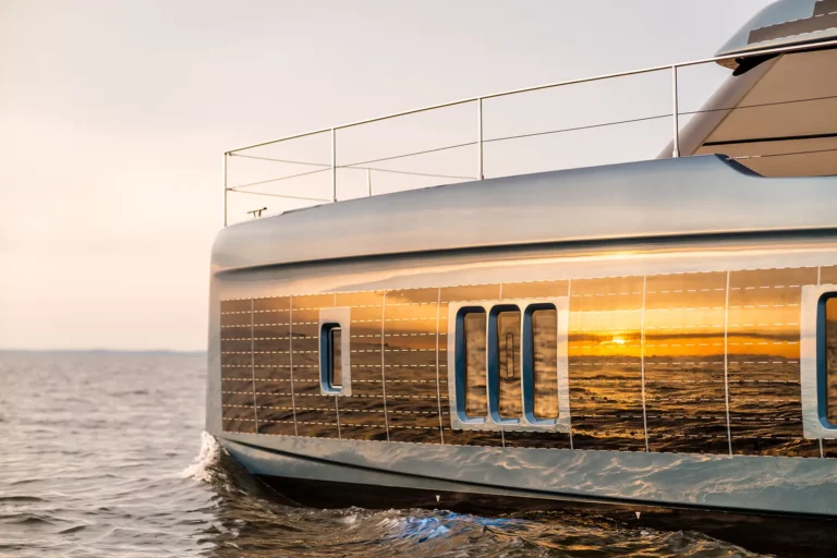 Nahaufnahme der Sunreef Power 60P Eco Yacht bei Sonnenuntergang, die reflektierenden Sonnenstrahlen betonen das elegante Design der Yacht und ihre fortschrittlichen Solarpanele.