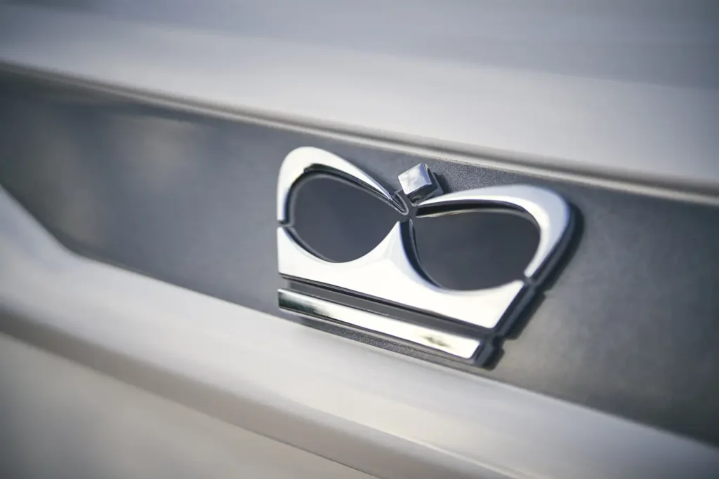 A shiny chrome Princess Yachts emblem shaped like a stylized crown, affixed to the side of a yacht